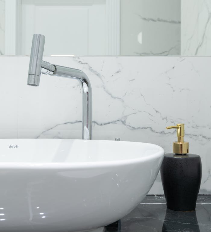 Elegant bathroom sink with chrome faucet and marble wall design.